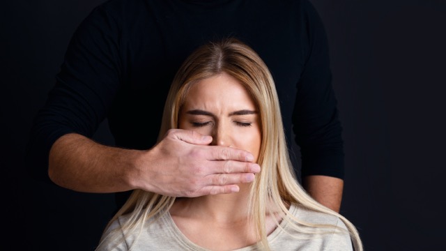 sychological and physical Sexual Shame: pressure man on woman. Male hand closes mouth of sad woman with closed eyes, panorama, copy space
