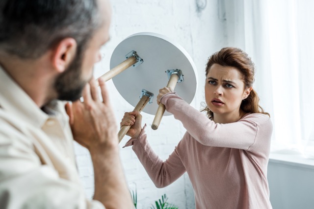 Narcissism In Marriage: selective focus of offended woman holding chair and looking at scared man at home