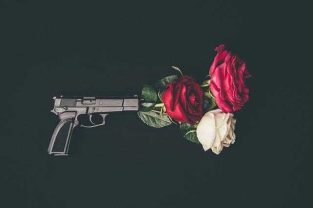 Weaponized Incompetence In Marriage: Top view of gun shooting with rose flowers isolated on black