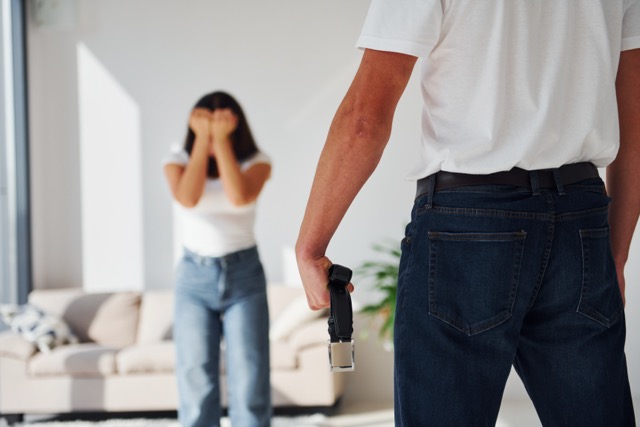 Weaponized Incompetence in Marriage: Violent aggressive young man with belt threatening his girlfriend at home.