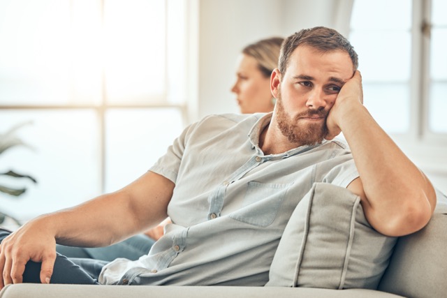 young Caucasian man with a beard looking unhappy and annoyed while sitting on the couch during an.