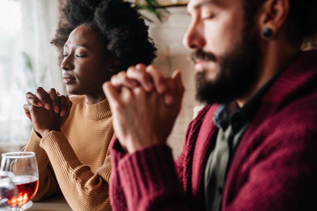 How to Stop Constant Arguing in a Relationship: Young happy multiethnic couple asking Lord to bless their food and day