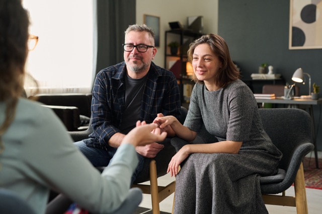 marriage couple sitting close together, attentively listening to a life coaching program.
