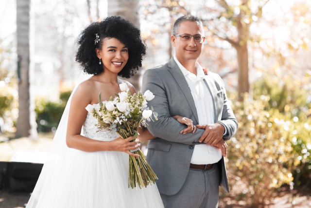 Portrait of a happy young bride getting walked down the aisle by her father on her wedding day.