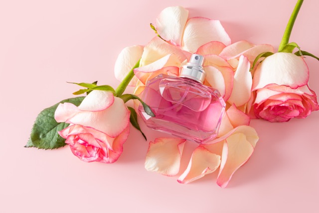 A beautiful crystal bottle of women's perfume with a chic fragrance lies on the petals of roses and rose flowers. empty bottle