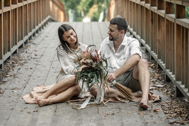 Happy marriage couple sit on the bridge and enjoy communication, a date in nature, and a love story.