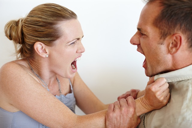 Close-up of a wife grabbing her husband's shirt in anger as they fight.
