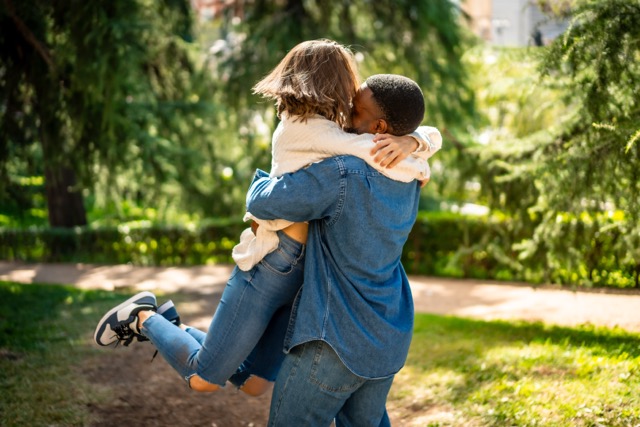 Multi-ethnic couple in love embracing and jumping together in a park