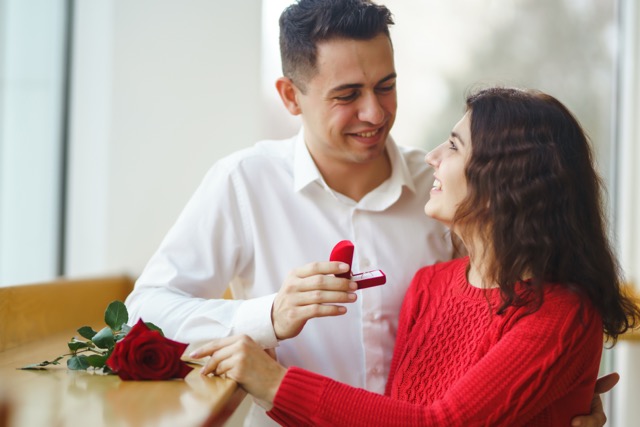 Handsome man proposing a beautiful woman to marry him in restaurant. Propose day concept.