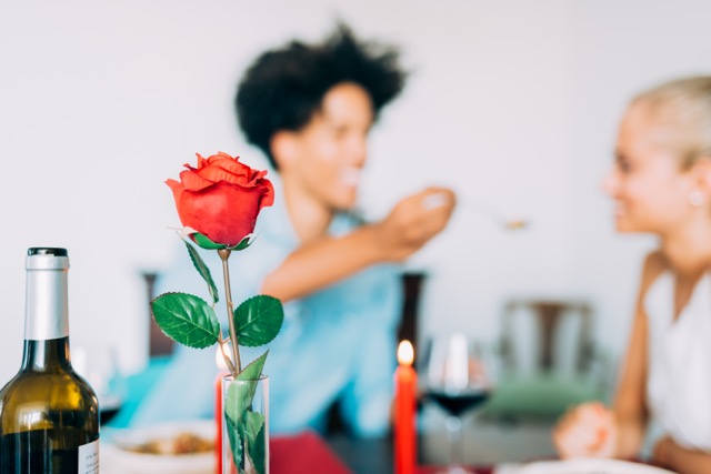 Rose Day Gift Ideas Beyond Flowers: Happy young in love interracial couple having romantic dinner on rose  day at home