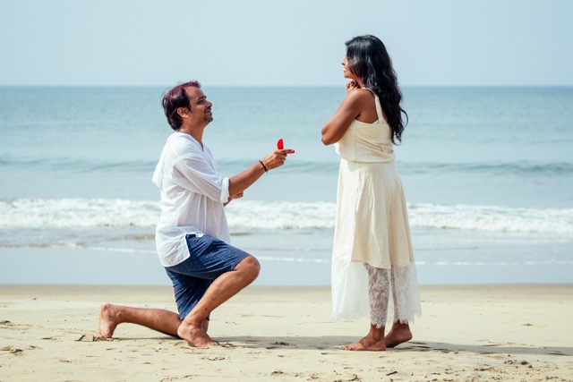 male making proposal with engagement ring and roses to his girlfriend at sea beach.Valentine day at Goa.