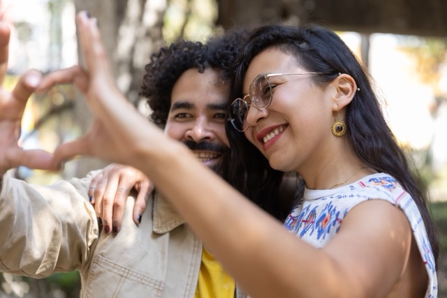 Marriage couple trying Two individuals standing side by side, making a heart shape with their hands.