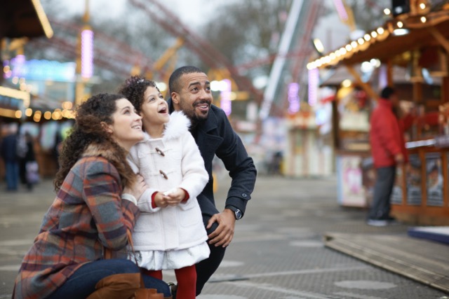 Mother and daughter in amusement park looking up smiling