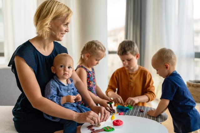 A mother or nursery teacher teaches her children to work with colorful play clay toys. Children creativity concept