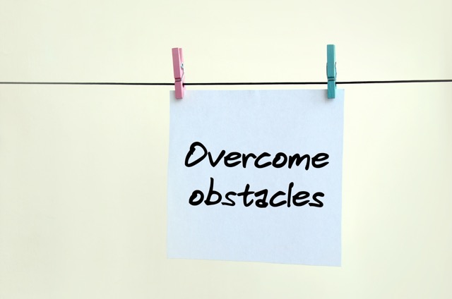 Overcome obstacles. Note is written on a white sticker that hangs with a clothespin on a rope on a background of beige wall