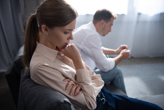 pensive upset couple in living room at home