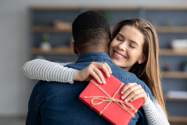 Portrait Of Happy Pleased Young Woman Received Romantic Gift From Her Black Boyfriend, Grateful Girlfriend Holding Present Box And Embracing Her Man, Multicultural Couple Celebrating Promise Day