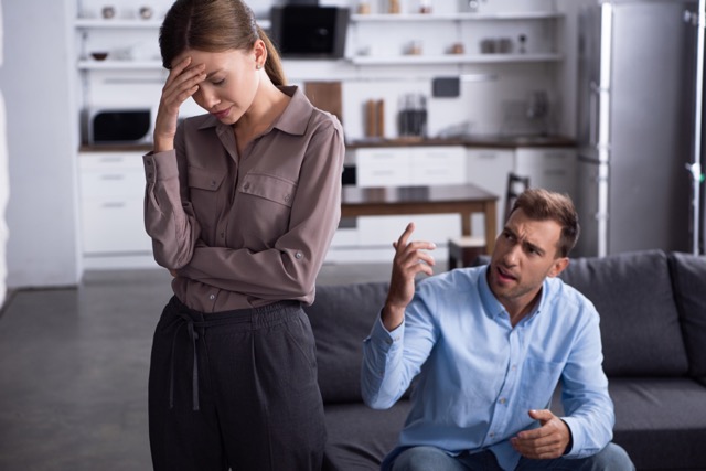 sad, tired woman and angry man sitting on sofa at home