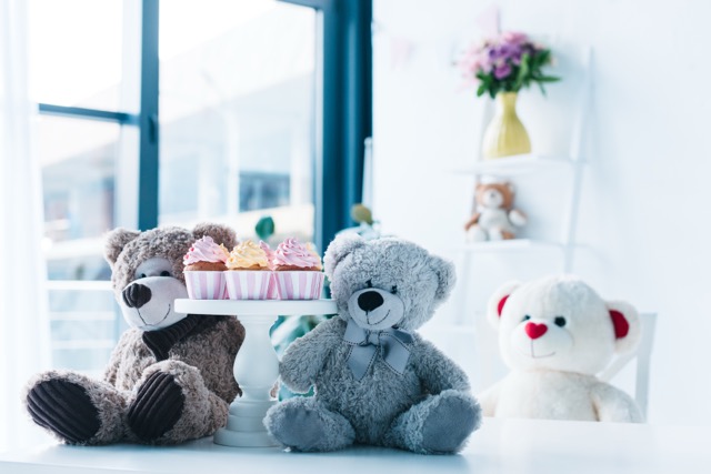 selective focus of teddy bears on table with cupcakes on stand