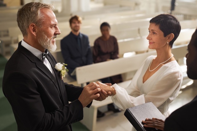 Side view portrait of smiling senior couple exchanging rings during wedding ceremony in church