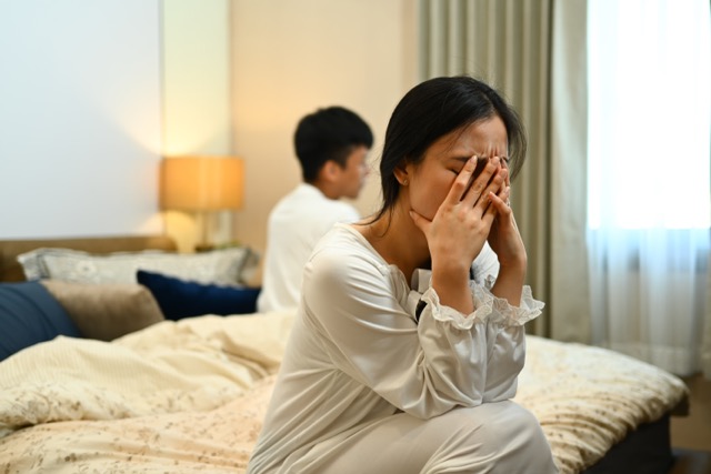 A young woman sitting and crying in bed after an argument with her husband. Relationship problems concept.