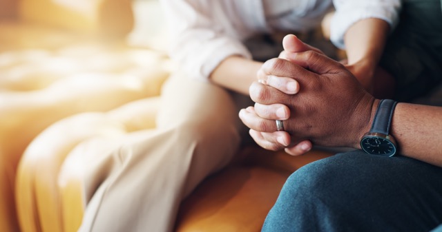 Holding hands, care, and marriage couple on sofa with support for parent marriage counseling together with bonding.