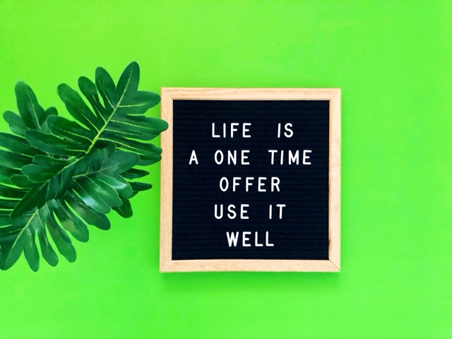  black letter board with the quote "LIFE IS A ONE TIME OFFER USE IT WELL" written in white letters.